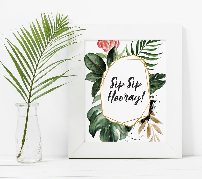 May include: A white framed print with a gold geometric frame and the text "Sip Sip Hooray!" surrounded by watercolor illustrations of tropical leaves and flowers.
