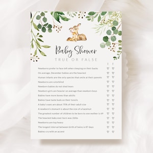 May include: Baby shower game card with a watercolour design. The card features a fawn illustration and greenery. The text reads "Baby Shower True or False" with a list of statements. The card is printed on a cream-coloured background.