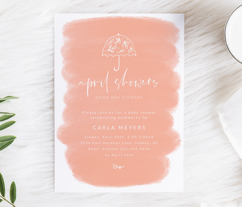 May include: A peach-colored baby shower invitation with a white watercolor background. The invitation features a white umbrella with floral details and the text "April Showers" in white cursive. The invitation also includes the text "Bring May Flowers" in white. The invitation includes the details of the baby shower, including the date, time, location, and RSVP information.