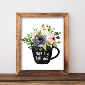 Pode incluir: Uma chávena de chá preta com fundo branco cheia de flores de aquarela. O texto "Make Tea Not War" está impresso na chávena.