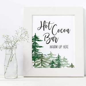 May include: A white framed printable sign with a watercolor illustration of green trees and the text "Hot Cocoa Bar Warm Up Here".