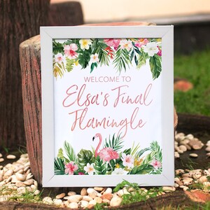 Op de afbeelding: Een wit ingelijst bord met een tropische bloemenrand en een roze flamingo. Het bord zegt "Welkom bij Elsa's Final Flamingle".