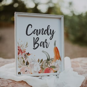 May include: White sign with a floral design and the text "Candy Bar" in black lettering. The floral design includes pumpkins, gourds, and leaves in shades of orange, brown, and green.