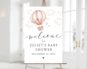 Puede incluir: Bienvenido a la Baby Shower de Juliet, cartel con una ilustración de un globo aerostático rosa y marrón, nubes blancas y estrellas rosas. La fecha es el 10 de diciembre de 2024.