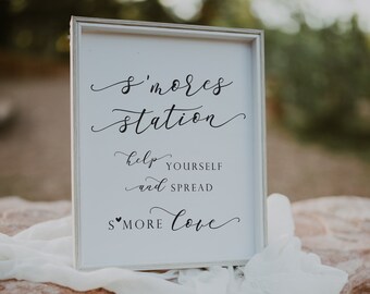 May include: White sign with black calligraphy text that reads "S'mores Station" with the words "Help yourself and spread s'more love" underneath.