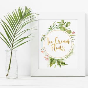 May include: A white frame with a watercolor illustration of green leaves and pink flowers surrounding a gold circle with the text "Ice Cream Floats" in gold lettering.