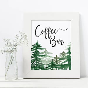 Puede incluir: Un marco blanco con una ilustraci&oacute;n de acuarela de una escena de bosque. El texto "Coffee Bar" est&aacute; escrito en letras cursivas negras.