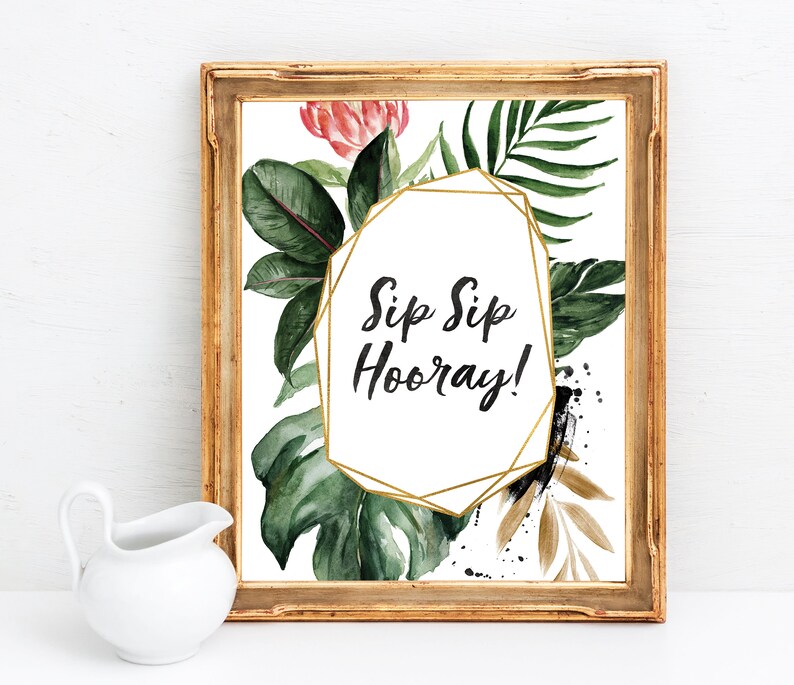 May include: A printable sign with a gold geometric frame and tropical leaves. The text on the sign reads "Sip Sip Hooray!"
