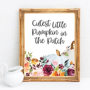 May include: A white framed print with the text "Cutest Little Pumpkin in the Patch" in black lettering. The print features a watercolor illustration of a white pumpkin with fall-colored flowers.