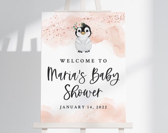 May include: A welcome sign for a baby shower with a pink watercolor background and a penguin wearing a flower crown. The sign says "Welcome to Maria's Baby Shower January 14, 2022".