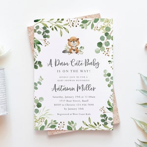 Könnte beinhalten: Eine Babyparty-Einladung mit einem grünen und braunen Blatt-Rand. Ein Cartoon-Biber befindet sich in der Mitte der Einladung. Der Text lautet "A Dam Cute Baby is on the way!" und enthält den Namen "Autumn Miller" sowie Details zur Babyparty.