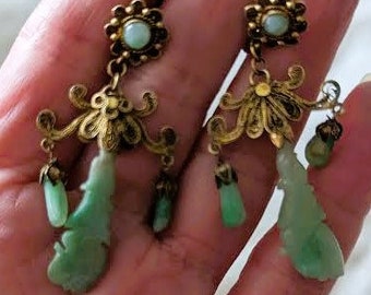 Peut inclure: Une paire de boucles d'oreilles pendantes avec des pendentifs en jade vert et des accents en filigrane doré. Les boucles d'oreilles présentent une pierre ronde verte au sommet et une plus petite pierre verte au bas de chaque pendentif.
