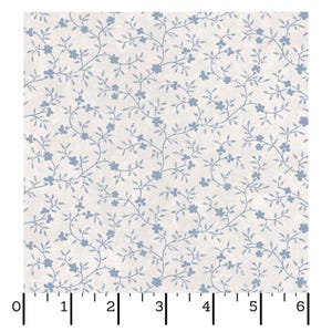 May include: A square of fabric featuring a repeating pattern of light blue floral vines and small flowers on a cream-colored background. The fabric is measured in inches, with markings from 0 to 6 inches.