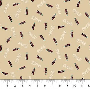 May include: Tan fabric with a repeating pattern of Coca-Cola bottles and the Coca-Cola logo in white. The bottles are red with green accents. A ruler is at the bottom of the image.
