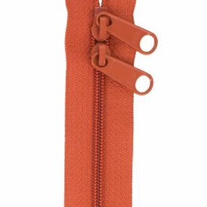 May include: A close-up of a rust-colored zipper with two pull tabs. The zipper is open and the teeth are visible.