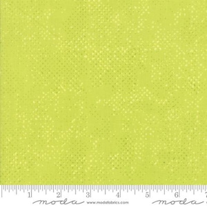 May include: A green fabric with a subtle white polka dot pattern. The fabric is shown with a ruler for scale.