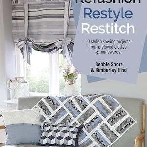 May include: A book cover titled "Refashion Restyle Restitch" with a gray sofa, pillows, and a patterned throw. The window has a striped valance. The book cover text says "20 stylish sewing projects from preloved clothes & homewares".