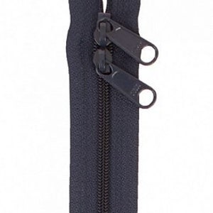 May include: A black zipper with two pull tabs. The zipper is closed and the pull tabs are at the top.
