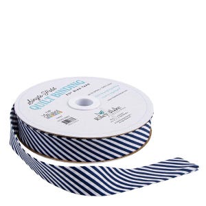May include: A spool of navy and white striped quilt binding tape. The tape is labeled "Single Fold Quilt Binding" and "2 1/4" Bias Tape." The tape is made of 50% wool and 50% cotton. The brand name "Riley Blake Designs" is also visible.