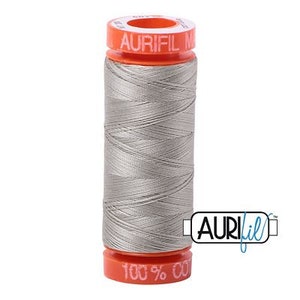 May include: A spool of silver gray thread with a bright orange label that reads "Aurifil 100% Cotton".