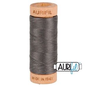 May include: A spool of gray thread with a wooden bobbin. The bobbin is labeled "Aurifil" and "Made in Italy".