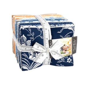 May include: A bundle of 10 Moda Fabrics fat quarters in a blue and white floral print with a white background. The fabric is tied together with a white ribbon and a measuring tape. The fabric is labeled "Moda Fabrics"