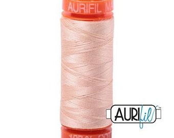 May include: A spool of Aurifil 100% cotton thread in a light peach color. The spool is labeled "Aurifil Made in USA" and "100% Cotton".