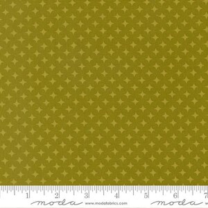 May include: Olive green fabric featuring a repeating pattern of small, four-pointed stars or diamonds. The textile has a visible woven texture and includes a white selvage edge at the bottom with the text moda and www.modafabrics.com printed.