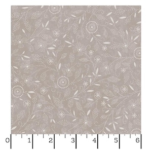 May include: Tan fabric with a repeating pattern of white dotted floral and leaf designs. The pattern includes stylized flowers, spirals, and leaves. The fabric is measured with a ruler in inches.