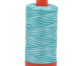 May include: A spool of teal and white thread with an orange base and top. The thread is tightly wound, creating a textured appearance. Ideal for sewing, embroidery, or other crafting projects.