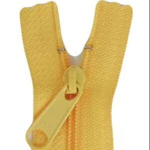 May include: A close-up of a yellow zipper with a matching pull tab. The zipper teeth are closed, and the pull tab is angled. The zipper is made of a durable material and is likely used for clothing or other fabric items.