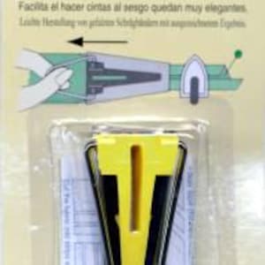 May include: A yellow and black bias tape maker for creating 1/2 inch bias tape. The tool is packaged on a white card with instructions in multiple languages. The text on the card reads "Bias Tape Maker [Width: 12 MM (1/2"])".