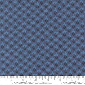 May include: A blue fabric featuring a repeating pattern of small, light blue flowers with dark gray stems and leaves. A white measuring tape is visible at the bottom, showing a scale of 7 inches with the text moda and modafabrics.com.