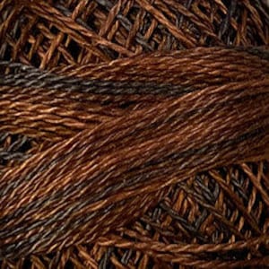 May include: Close-up of a ball of brown and black yarn. The yarn appears to be a blend of colors, with strands of dark brown, light brown, and black interwoven. The texture of the yarn is visible, with individual fibers creating a textured surface. The yarn is tightly wound.