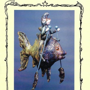 Könnte beinhalten: Ein farbenfrohes, 40,6 cm großes Stoffpuppenmuster für einen Fischer, der auf einem Fisch reitet. Das Muster trägt den Titel "The Fisherman" und stammt von Julie McCullough. Das Copyright liegt bei ©1999 Magic Threads Alle Rechte vorbehalten.