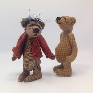 May include: Two handmade plush teddy bears, one with a red jacket and the other with a brown and white checked pattern.