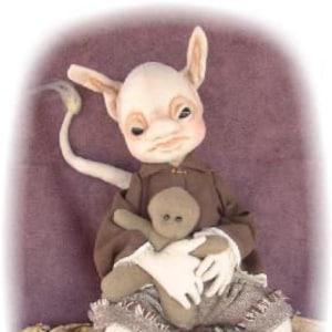 Könnte beinhalten: Eine skurrile, handgefertigte Puppe mit großen Ohren, einem langen Schwanz und einem braunen, zerfetzten Outfit. Die Puppe hält ein kleines, braunes Plüschtier.