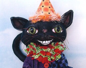 May include: A black cat figurine with green eyes, wearing a party hat and a ruffled collar. The cat is dressed in a purple and blue patchwork outfit and holds a bag with a pumpkin design. The base reads "Happy Halloween".