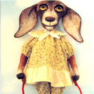 May include: A handmade doll with a dog head, wearing a yellow floral dress and black shoes, holding a red skipping rope.