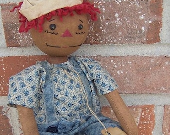 May include: A handmade rag doll with a brown face, red yarn hair, and a cream-colored cap. The doll wears a blue patterned dress and overalls. A tag reads "Uncle Andy".