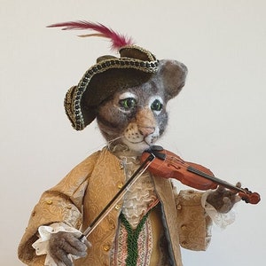 May include: A gray and white cat wearing a gold and black hat with a red feather, a gold and brown coat, black pants, and gold shoes, playing a violin.