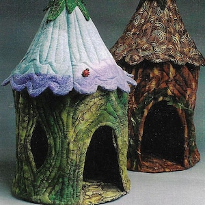 May include: Two whimsical, fabric-covered houses, one green with a purple flower top and a ladybug, the other brown with a swirling pattern.