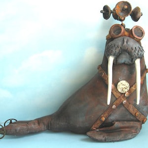 May include: A brown, steampunk-style walrus figurine with a propeller hat, goggles, and a leather harness with rivets. The walrus has large, white tusks and is on wheels.