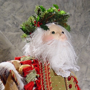 May include: A decorative Santa Claus figure with a white beard and a green and red outfit. The figure has a wreath of holly and berries on its head. The outfit is trimmed with gold and red tassels, and a white lace collar.
