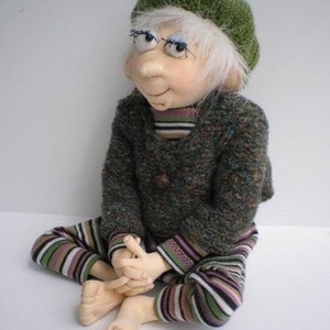 May include: A handmade doll with white hair, wearing a green knitted beret, a green and brown sweater, and striped pants.