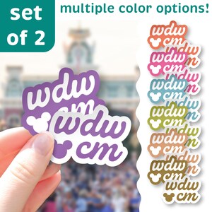 May include: A set of two stickers with the text "wdw cm" in a stylized font, with a Mickey Mouse head. The stickers are purple and white. Additional stickers in various colors are shown, with the text "multiple color options!"