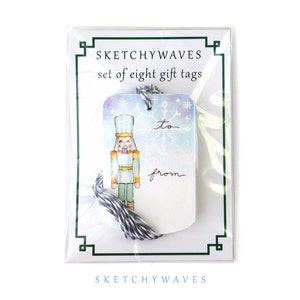 May include: A set of eight watercolor gift tags featuring a nutcracker illustration with a snowflake background. The tags are white with a blue, purple, and green watercolor wash. The tags have the words "to" and "from" printed on them.