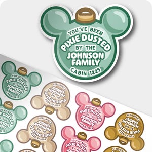 May include: A sheet of die-cut stickers shaped like mouse-eared Christmas ornaments in various colors including green, pink, tan, and brown. Each sticker features the text "YOU'VE BEEN PIXIE DUSTED BY THE JOHNSON FAMILY CABIN 1225" in white.