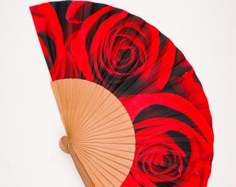 May include: A red and black hand fan with a floral design featuring red roses. The fan is made of wood and has a black handle.