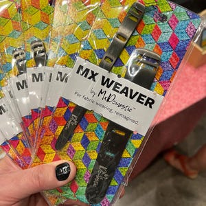 May include: Several packages of MX WEAVER weaving tools by MxDomestic. Each package contains a black and silver tool with the text "MX WEAVER" and "For fabric weaving, reimagined." The packaging has a colorful geometric pattern.